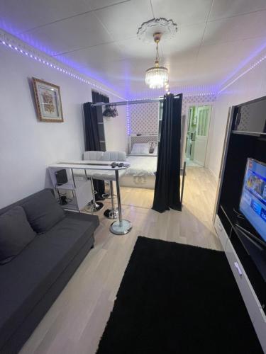 - un salon avec un canapé, une table et des lumières violettes dans l'établissement Jolie petite maison avec un grand jardin, à Montmagny