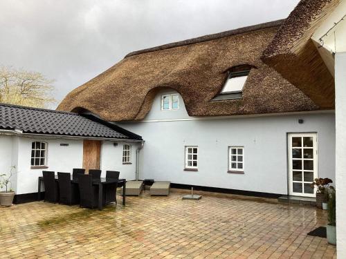 a white house with a thatched roof and a patio at 12 person holiday home in Sønder Omme-By Traum in Sønder Omme