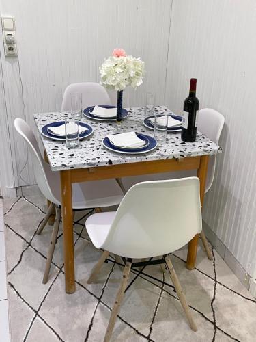 - une table avec des chaises blanches et une bouteille de vin dans l'établissement Jolie petite maison avec un grand jardin, à Montmagny
