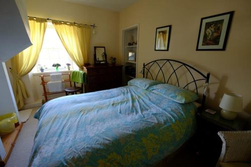 a bedroom with a bed with a blue comforter and a window at Cosy cottage flat in Inveraray