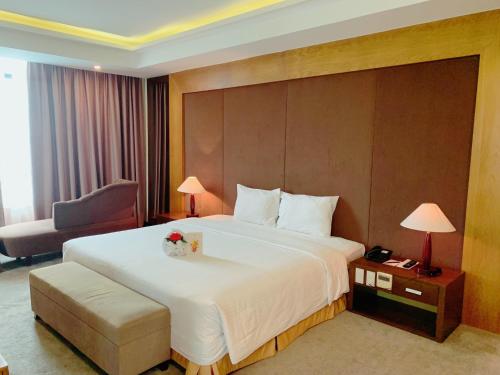 a hotel room with a large bed and a chair at Muong Thanh Luxury Nhat Le Hotel in Dong Hoi
