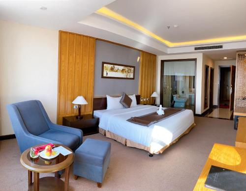 a hotel room with a bed and a blue chair at Muong Thanh Luxury Nhat Le Hotel in Dong Hoi