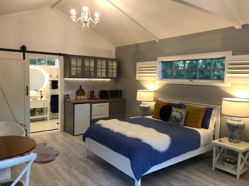 a bedroom with a blue bed and a kitchen at Hamptons In Rye Blue Cottage 3 Mins from Hot Springs! in Rye