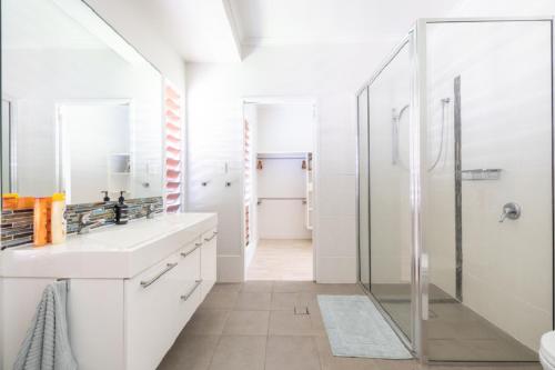 Un baño blanco con ducha y lavabo. en The Retreat, en South Mission Beach
