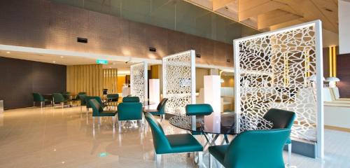 Ambassador Transit Lounge Terminal 2 في سنغافورة: غرفة انتظار وكراسي خضراء وطاولة