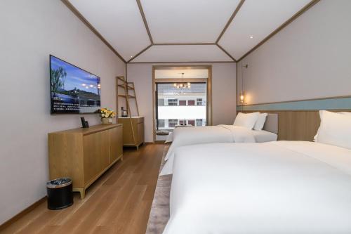 Habitación de hotel con 2 camas y TV de pantalla plana. en Qianhe International Hotel, en Jiuzhaigou