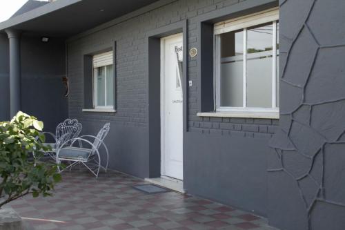 a gray house with a white door and a chair at Guanaco Hostel in Puerto Madryn