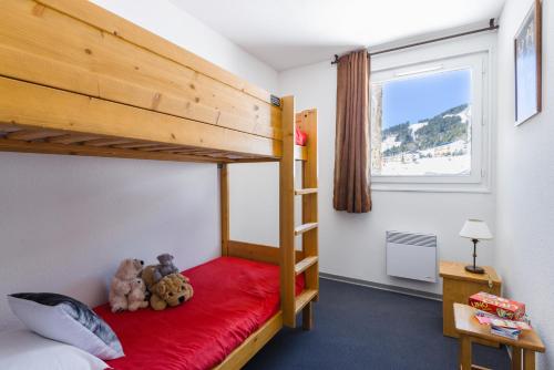 - une chambre avec des lits superposés avec des ours en peluche sur une couverture rouge dans l'établissement Lagrange Vacances L'Orée des Cîmes, aux Angles