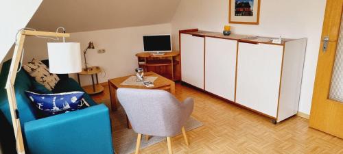 a living room with a blue chair and a desk at FeWo-1-OG-links in St. Peter-Ording