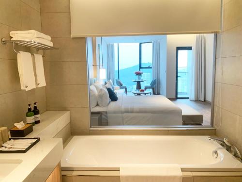 a bathroom with a bath tub and a bedroom at HB Serviced Apartment - Alacarte Hạ Long in Ha Long