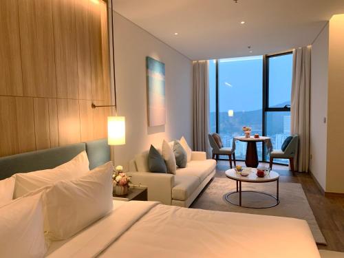 Habitación de hotel con cama y sala de estar. en HB Serviced Apartment - Alacarte Hạ Long, en Ha Long