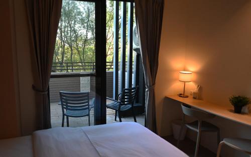 ein Hotelzimmer mit einem Bett und einem Balkon mit Stühlen in der Unterkunft Lütel Hotel Xpark Gloria Outlets Shin Kong Cinemas in Dayuan