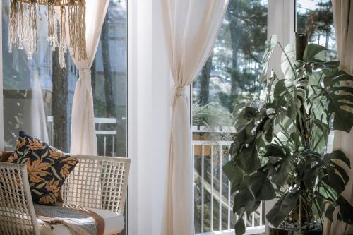 a window with curtains and a chair and a plant at Dahlia Dalat in Xuan An