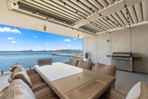 a dining room with a view of the water at Whispering Waters Soldiers Point Rd 3 143 in Soldiers Point