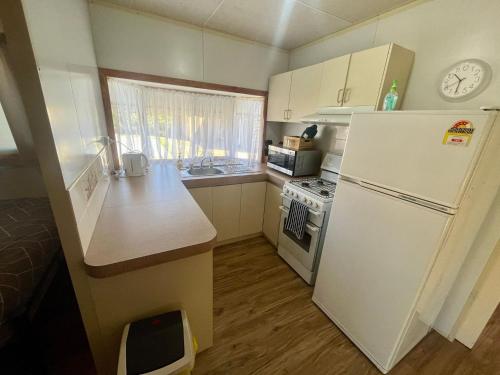 a small kitchen with a white refrigerator and a stove at Family Getaway Cabin 50 in Broadwater