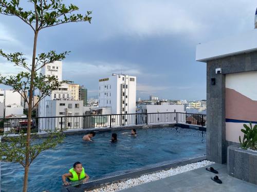 峴港的住宿－LAGOM APARTMENT AND HOTEL，一群人在一座大楼的游泳池里