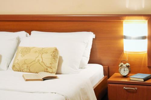 a bedroom with a bed with a clock and a book at Hotel Rex in Belgrade