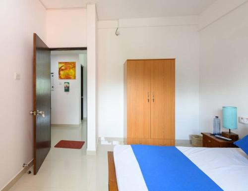 a bedroom with a blue and white bed and a wooden door at Flora Residencies Apartment in Battaramulla in Colombo