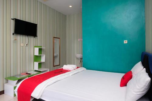 1 dormitorio con cama blanca y pared verde en RedDoorz Syariah near Gardu Pandang Dieng en Kejajar