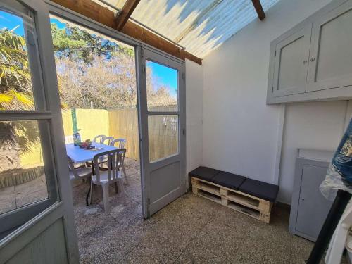 une porte menant à une terrasse avec une table et une fenêtre. dans l'établissement Maison 2 pièces avec mezzanine, à 400m de la plage, parking, jardin privé, 6 couchages - Saint-Hilaire-de-Riez - FR-1-224C-218, à Saint-Hilaire-de-Riez
