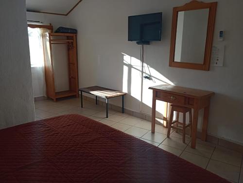 Cette chambre comprend un bureau, une table et un miroir. dans l'établissement Sierra Hotel, à Areponapuchi