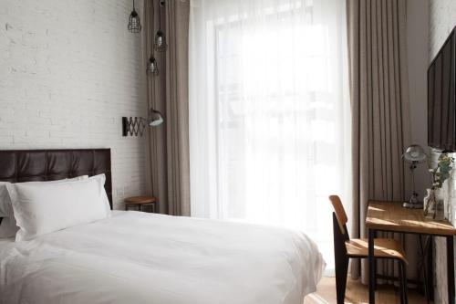 a bedroom with a white bed and a desk and a window at Yi Stack Hotel Beijing in Beijing
