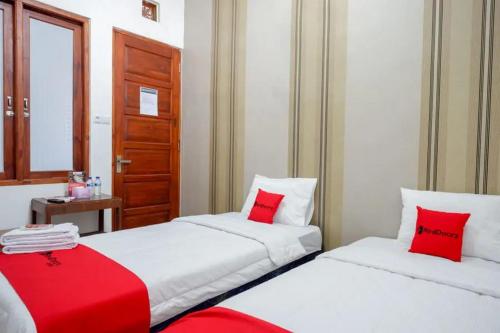 スラカルタにあるRedDoorz near Stasiun Purwosariの赤い枕付きのベッド2台が備わる客室です。