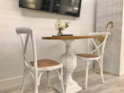 a table with two chairs and a vase with flowers on it at Hamptons In Rye Green Cottage 3 Mins to Hot Springs! in Rye
