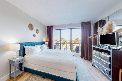 a bedroom with a bed and a television and a balcony at Pirates Bay A309 in Fort Walton Beach