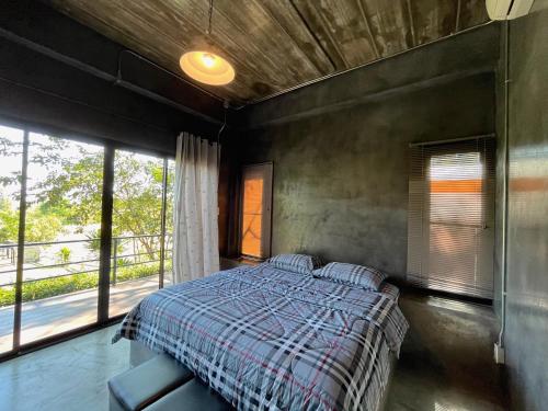 a bedroom with a bed and a large window at Moon Village Khaoyai Holiday Home in Pong Talong