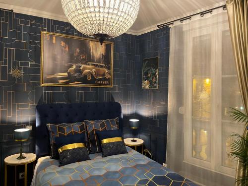 Dormitorio azul con cama y lámpara de araña en Nos studios au centre ville à Dole, en Dole
