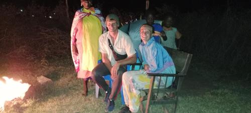 a group of people sitting in chairs next to a fire at Maasai homestay camping in Sekenani