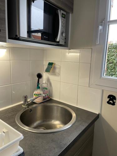 un comptoir de cuisine avec un évier et un micro-ondes dans l'établissement Location maison vacances 4 pers proche plage chez Lili Berck, à Berck-sur-Mer