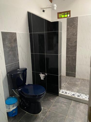 a bathroom with a black toilet and a shower at River house in Jardin