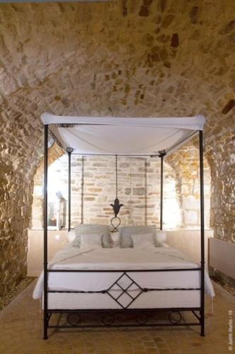 - une chambre avec un lit à baldaquin dans un mur en pierre dans l'établissement Casa de la félicita, à Vézénobres