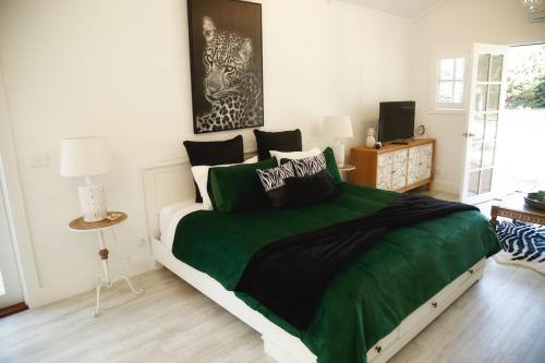 - une chambre avec un grand lit et une couverture verte dans l'établissement Hamptons In Rye Green Cottage 3 Mins to Hot Springs!, à Rye