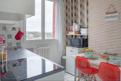 une cuisine avec un comptoir et une table avec des chaises rouges dans l'établissement T1 cocooning à l’Hôtel de Ville, à Charleville-Mézières