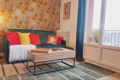 a living room with a green couch with colorful pillows at T1 cocooning à l’Hôtel de Ville in Charleville-Mézières