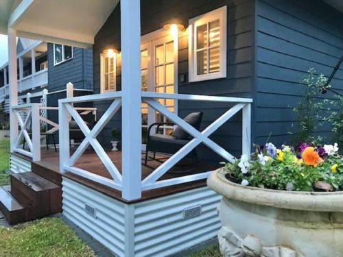 a front porch of a blue house with a patio at Hamptons In Rye Green Cottage 3 Mins to Hot Springs! in Rye