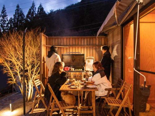 a group of people sitting around a table on a patio at Dot Glamping 富士山 in Fujikawaguchiko