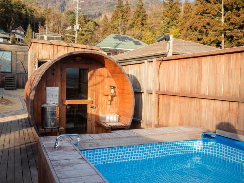 a wooden building with a swimming pool next to a house at Dot Glamping 富士山 in Fujikawaguchiko
