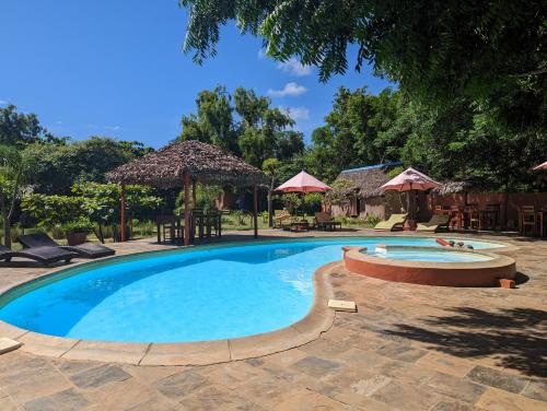 una piscina in un cortile con sedie e ombrelloni di Hotel Lakana Ramena a Antsiranana