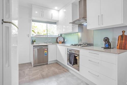 a kitchen with white cabinets and stainless steel appliances at Stylish Beachside Comfort Your Brighton Retreat in Brighton