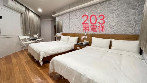 two beds in a hotel room with a sign on the wall at 町宿溫泉旅館 in Jiaoxi