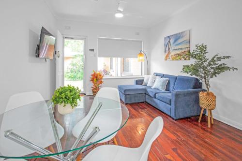 a living room with a blue couch and a glass table at Stylish Beachside Comfort Your Brighton Retreat in Brighton