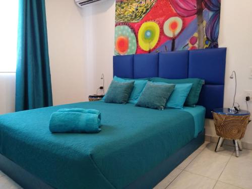 a blue bed in a room with a painting on the wall at Turquoise Villa in Paradijs