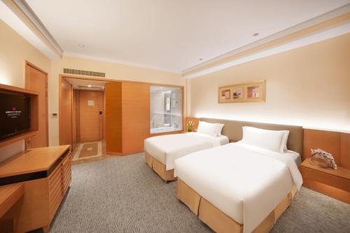 a hotel room with two beds and a flat screen tv at Millennium Hotel Chengdu in Chengdu