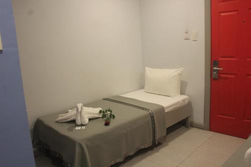 a small room with a bed and a red door at ML SUITES CEBU in Cebu City