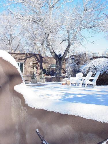 a snow covered yard with white chairs and a tree at Inn on the Rio in Taos