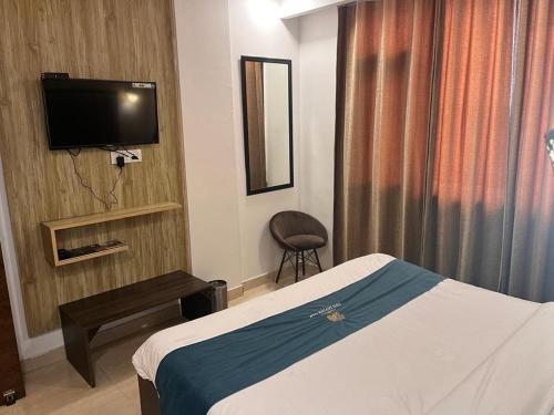 a hotel room with a bed and a television at The Divine Oak in Katra